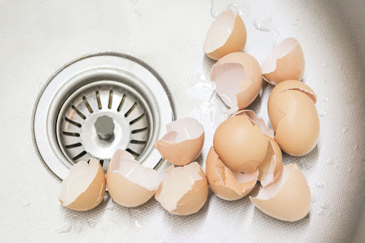Multiple egg shells sitting in sink drain.
